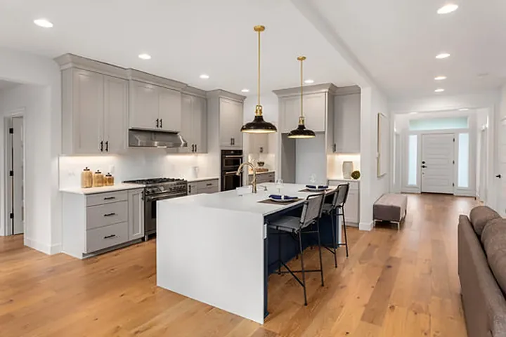 Grey cabinets with a white island and brass pendants